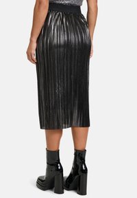 Metallisch schwarze, plissierte Midi-Rock mit einem breiten elastischen Bund, kombiniert mit glanzvollen schwarzen Plateaustiefeletten.