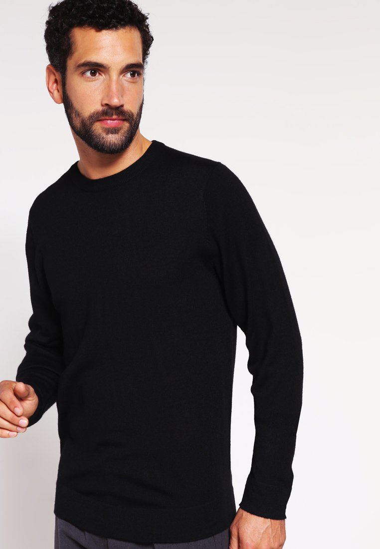 Črni pulover z dolgimi rokavi in okroglim izrezom, narejen iz mehkega materiala, z ribastimi manšeti in gladko teksturo, na sebi ga ima moški model.