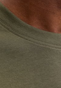 Olivengrøn bomuld t-shirt med rund halsudskæring. Har et glat, struktureret stof og en tætsiddende krave.