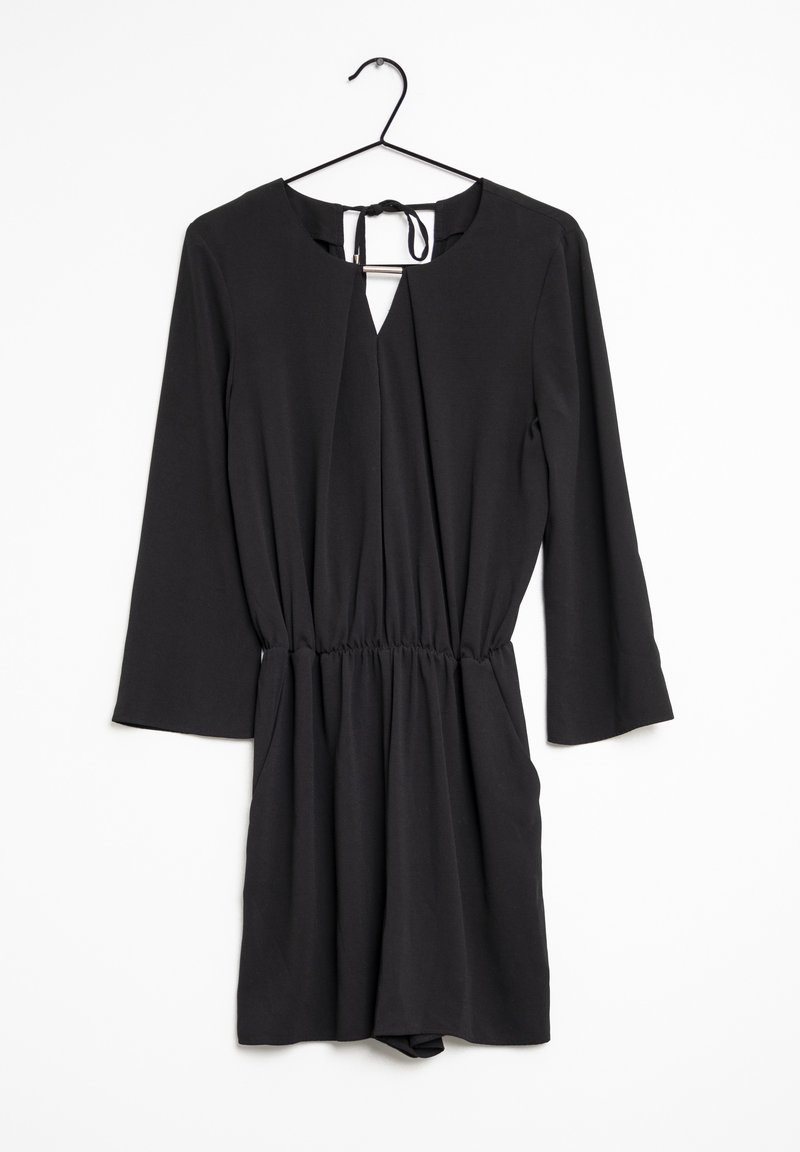 Svart jumpsuit med lång ärm, nyckelhålsringning, rynkad midja och slät yta, hängande på en svart krok mot en vit bakgrund.