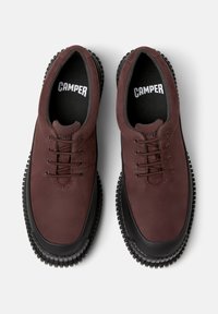 Scarpe stringate color mogano con suola in gomma nera testurizzata, con il nome del marchio "CAMPER" sulle solette e una finitura in pelle liscia.