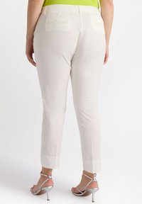 Lichtbeige slim-fit broek met een gladde textuur, twee achterzakken en een cropped zoom, gecombineerd met zilveren hoge hakken.