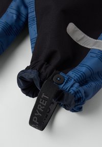 Blåt stof med et mønsterdesign, der har en elastisk manchet og sort hardware. Inkluderer et sort mærke med hvid tekst.