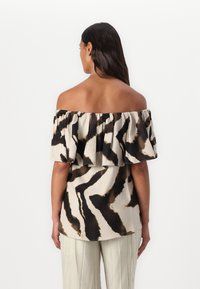 Beige off-shoulder paita, jossa on mustia ja ruskeita abstrakteja kuvioita, rypistyneellä kaula-aukolla ja rento leikkaus. Sujuva kankaan pinta.