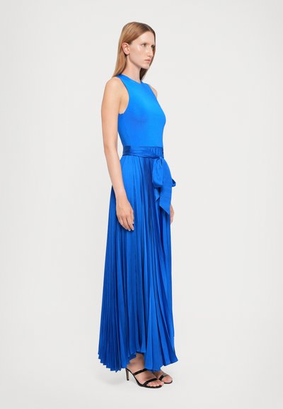 Blaues ärmelloses Kleid mit einem taillierten Oberteil und einem gefalteten, bodenlangen Rock, ausgestattet mit einem gebundenen Taillengürtel und schwarzen High-Heels.