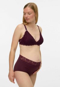 Tumši burgundijas krāsas mežģīņu braletis ar regulējamiem siksniņām, kombinēts ar augsta vidukļa saskaņotiem biksītēm, kurām ir mežģīņu akcentēta jostasvieta.