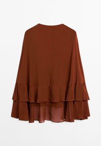 Cappa marrone a strati con texture arricciata. Presenta un tessuto liscio e un collo rotondo, che si porta a diverse lunghezze all'orlo.