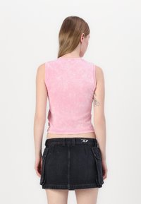 Rosa ermeløs topp med en falmet tekstur, kombinert med et svart denimskjørt med lommer og en sølvfarget detalj på livet.