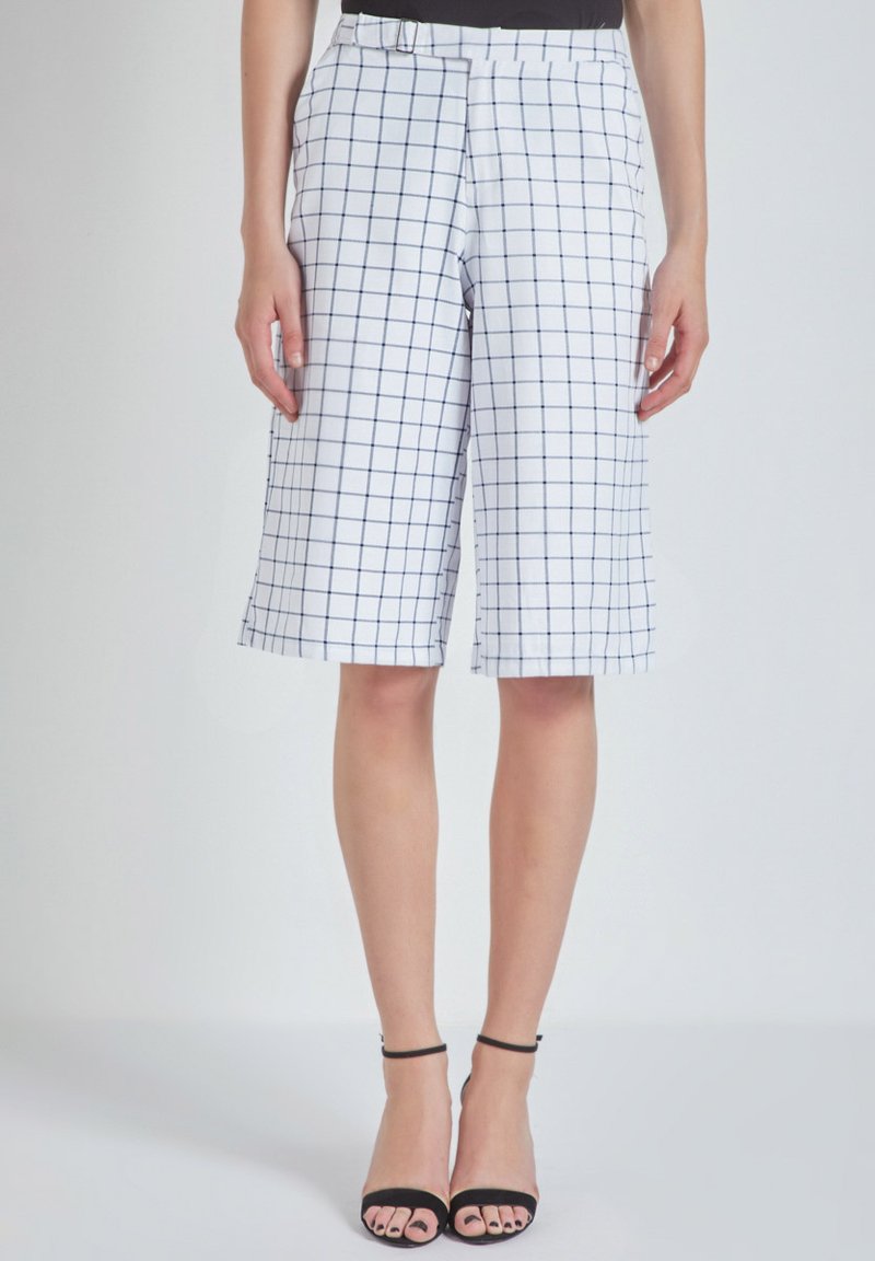 Pantalones cortos a cuadros blancos con un patrón de cuadrícula en color marino, con pliegues en la parte delantera y bolsillos laterales. Corte ajustado, que termina justo por encima de la rodilla.