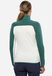 Veste en polaire avec une partie supérieure verte et une partie inférieure texturée blanche, col haut, motifs côtelés et design ajusté.