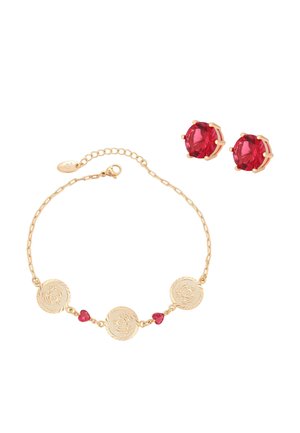 Bracelet chaîne en or avec trois pièces rondes gravées et deux petites pierres rouges en forme de cœur, assorti à des boucles d'oreilles clous avec pierres précieuses rouges rondes.