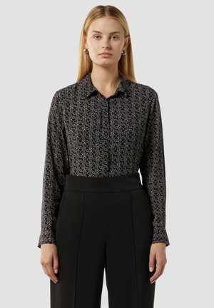 Black patterned shirt with a collared neckline, featuring a subtle swirl design in light color, paired with high-waisted black trousers.
