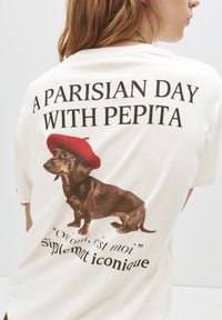 Krémové tričko s potlačou hnedého jazvečíka v červenom baretku. Nad grafikou je text "PARÍŽSKY DEŇ S PEPITOU".