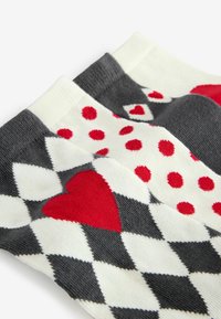 Kolorowe skarpetki z czarno-biało-szachowniczym wzorem, czerwonymi sercami oraz czerwonymi kropeczkami, wykonane z miękkiego materiału i wykończone ściągaczami.