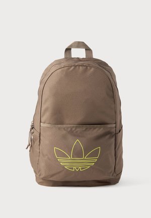 Sac à dos marron avec poche zippée à l'avant et logo Adidas trefoil jaune sur un fond uni.