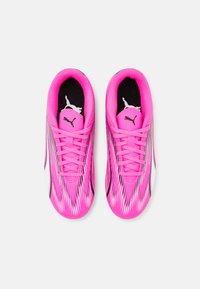 Scarpe da atletica Puma di un vivace colore rosa con una parte superiore testurizzata, accenti neri e un design a motivi; con fodera interna e lacci neri.