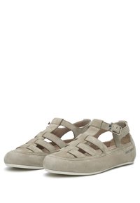 Chaussures en suède beige clair avec des bandes découpées et une fermeture à boucle sur le côté. Elles présentent un bout rond et un intérieur rembourré pour un confort optimal.