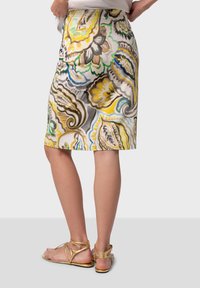 Jupe à motifs floraux dans des couleurs vives comprenant du jaune, du vert et du bleu. Fabriquée en tissu léger, longueur genou avec une taille ajustée.