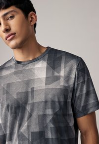 Kurzärmeliges T-Shirt mit grafischem Muster in Grautönen, ausgestattet mit strukturiertem Stoff und rundem Ausschnitt.