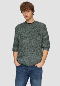 Donkergrijze gebreide trui met een textuurpatroon, ronde halslijn en geribde manchetten, gecombineerd met lichtblauwe denim jeans.
