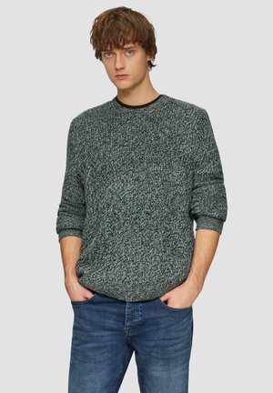 Dark gray knit sweater with a textured pattern, crew neckline, and ribbed cuffs, paired with light blue denim jeans.