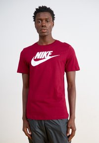 Camiseta de algodón roja con un destacado logo blanco de Nike en la parte delantera. Diseño clásico de cuello redondo con mangas cortas.