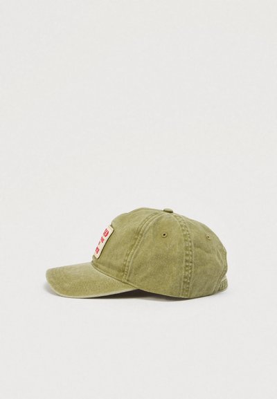 Πράσινο βαμβακερό καπέλο μπέιζμπολ με κυρτό γείσο, που διαθέτει κόκκινο και άσπρο ορθογώνιο έμβλημα στο μπροστινό μέρος και λεπτομέρειες ραφών κατά μήκος των ραφών.