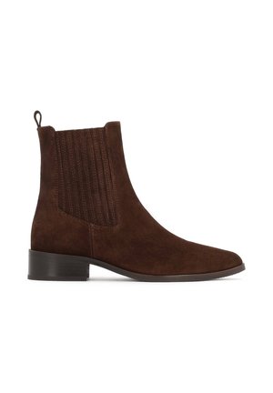 Bottine en suede marron à bout pointu, avec des panneaux latéraux élastiques et un petit talon carré. Dispose d'une languette à l'arrière pour un enfilage facile.