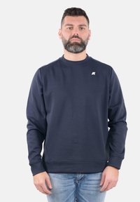 Felpa blu navy, colletto rotondo, maniche lunghe, texture morbida, polsini e orlo a costine, presenta un piccolo logo bianco sul lato sinistro del petto.