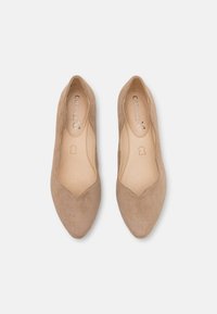 Beżowe zamszowe baleriny z wydłużonym noskiem, głębokim wycięciem w kształcie litery V oraz przeszywaniami. Gładka podszewka wnętrza i subtelnie widoczne logo.