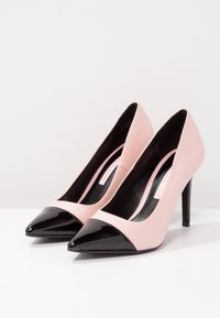 Rosa läder högklackade skor med en svart lackläder spetsig tå och detaljer. Har en elegant design och en smal hög klack.