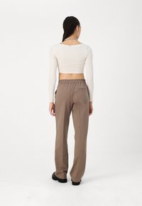 Långa, löst sittande beige byxor med elastisk midja, kombinerat med en åtsittande långärmad krämfärgad topp. Mjuk textur, minimalistisk design.