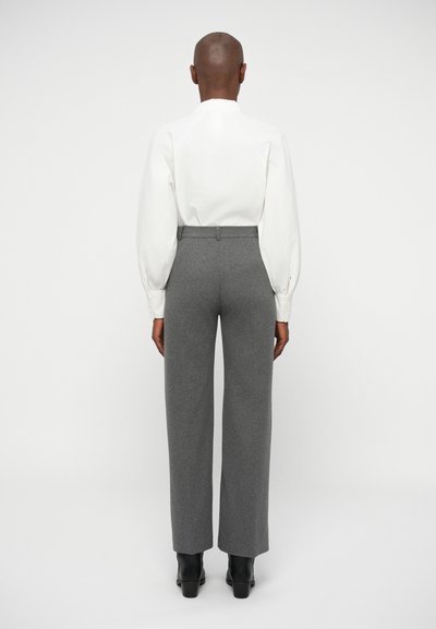 White, puff-sleeved shirt paired with high-waisted, wide-leg gray trousers. Smooth fabric with subtle texture, finished with black ankle boots.