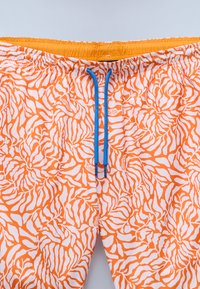 Oranje zwembroek met een witte abstracte bladdessin, elastische tailleband met een gele binnenkant en een blauwe trekkoord.
