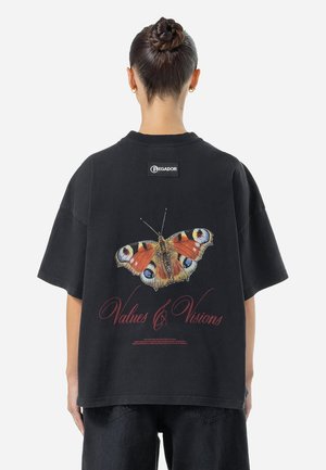 Zwarte oversized t-shirt met een kleurrijke vlinderafbeelding op de achterkant en de tekst "Values & Visions" in het rood. Geribbelde kraag, korte mouwen.