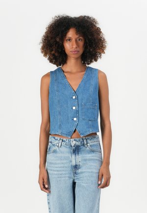 Denim cropped vest with a v-neck, button closure, and a side pocket. The fabric is light blue with stitch detailing and a smooth texture.