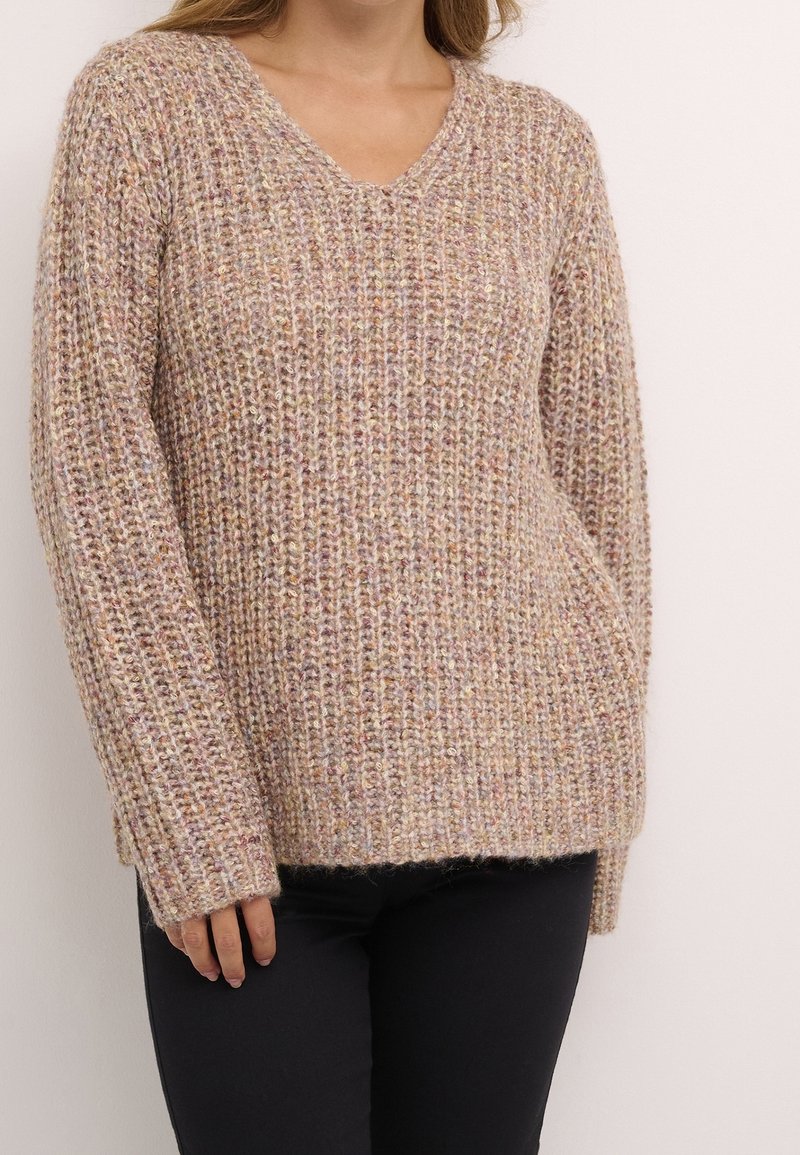 Pull en laine de couleur beige atténué avec un ribbing texturé. Il présente un col en V, des manches longues et une coupe décontractée, avec des fils multicolores subtils.
