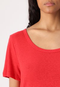 T-shirt rosso a maniche corte con scollatura ampia. Realizzato in un tessuto morbido con una sottile texture e una vestibilità rilassata.