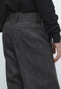 Pantaloni grigi scuri realizzati in tessuto testurizzato, con un taglio slim, tasche posteriori e una vita liscia.