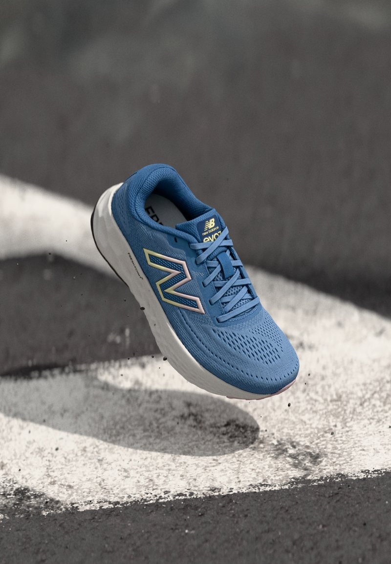 Scarpa sportiva blu con upper in rete, chiusura con lacci e suola bianca. Presenta un logo multicolore con accenti chiari e una texture perforata.