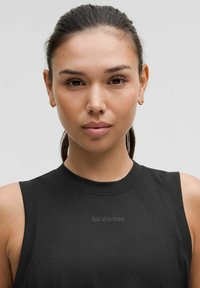 Top atletico senza maniche di colore nero con scollatura rotonda e dettagli in rete. Presenta un sottile logo "lululemon" al centro davanti. Texture liscia.