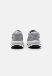 Grå atletik sko med en mesh overdel, polstret hvid mellemsål og sort ydersål. Har et markant hældesign og Nike-logo.