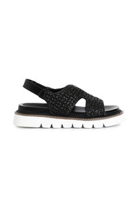 Mustat kudotut slingback-sandaalit, joissa on leikkauksia, teksturoitu päällinen ja paksu valkoinen pohja. Varustettu kiiltävällä mustalla pinnalla ja säädettävällä hihnalla.