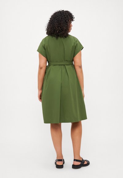 Vestito verde lungo fino al ginocchio con maniche corte e cintura da annodare in vita. Presenta una texture pulita e liscia e un design semplice e morbido.