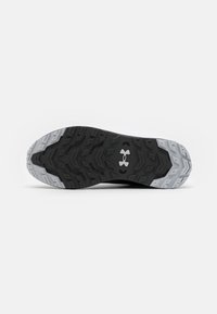 Suola di scarpa atletica nera e grigia con un motivo testurizzato che presenta forme esagonali e triangolari; logo ben visibile in bianco.