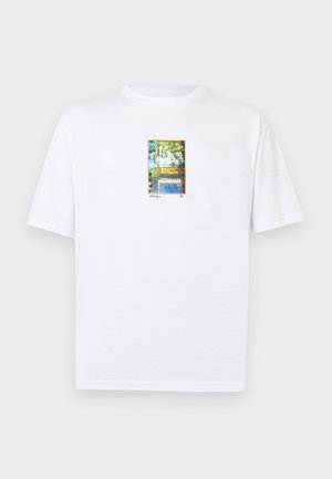 Λευκό T-shirt με μικρό πολύχρωμο ορθογώνιο εκτύπωμα με δέντρα, ποτάμι και γέφυρα στην κεντρική περιοχή του στήθους.