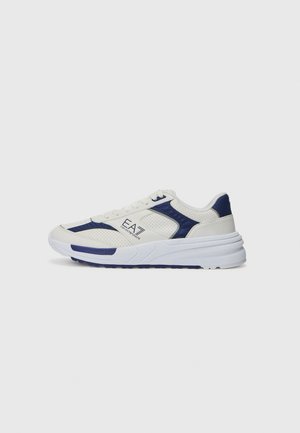 White and navy mesh sneakers with a textured upper, featuring perforated accents, flat laces, and a thick rubber sole.