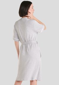 Vestido de algodón gris con mangas cortas, cintura ceñida, diseño a la altura de la rodilla y aberturas laterales. Textura suave y estilo minimalista.