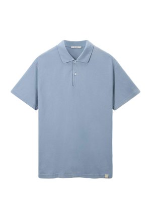 T-shirt polo bleu ciel en tissu doux, manches courtes, patte de boutonnage à trois boutons, et un design légèrement texturé avec une petite étiquette logo à l'ourlet.