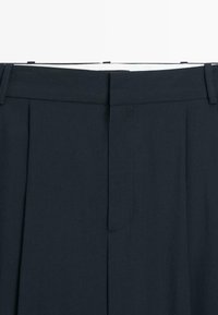 Marineblaue, plissierte Hose mit glatter Textur, tailliertem Bund und einer dezenten Bügelfalte vorne für einen formellen Look.